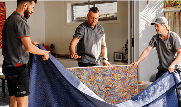 Team members moving a wrapped rug indoors